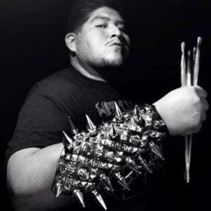 Black and white photo of Dwayne Manuel wearing a fore arm cover with spikes and holing paint brushes with his hand
